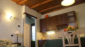 Un espacio habitable compacto con kitchenette, zona de comedor con mesa y sillas, y sofá.