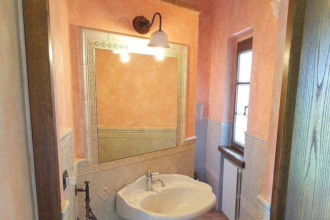 A bathroom with a large mirror, a sink, and a light fixture above the mirror.