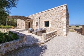 Un bâtiment en pierre doté d’une terrasse et d’une cour intérieure recouverte de gravier.