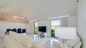 A modern living room with a sofa, TV, and a lamp. - Holiday Home "Es Gassons" with Pool, Wi-Fi, AC, Terrace & Garden (María de la Salut)