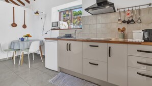 A kitchen with a window, white cabinets, a small table with chairs, and a ceiling fan. - Tiled House with Sea & Mountain Views, Wi-Fi, Terrace, Garden, Pet-Friendly (La Orotava)
