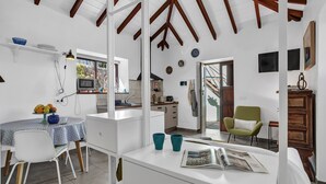 A modern kitchen with white cabinets, a dining area with a white table and chairs, and a green armchair. - Tiled House with Sea & Mountain Views, Wi-Fi, Terrace, Garden, Pet-Friendly (La Orotava)