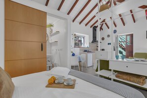 Moderni hotellihuone, jossa on sänky, aamiaistarjoilu, pieni keittiö ja näkymä ulos.