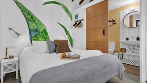 A modern bedroom with a large bed, a wooden wardrobe, a bathroom with a white sink, and a large mirror. - Tiled House with Sea & Mountain Views, Wi-Fi, Terrace, Garden, Pet-Friendly (La Orotava)