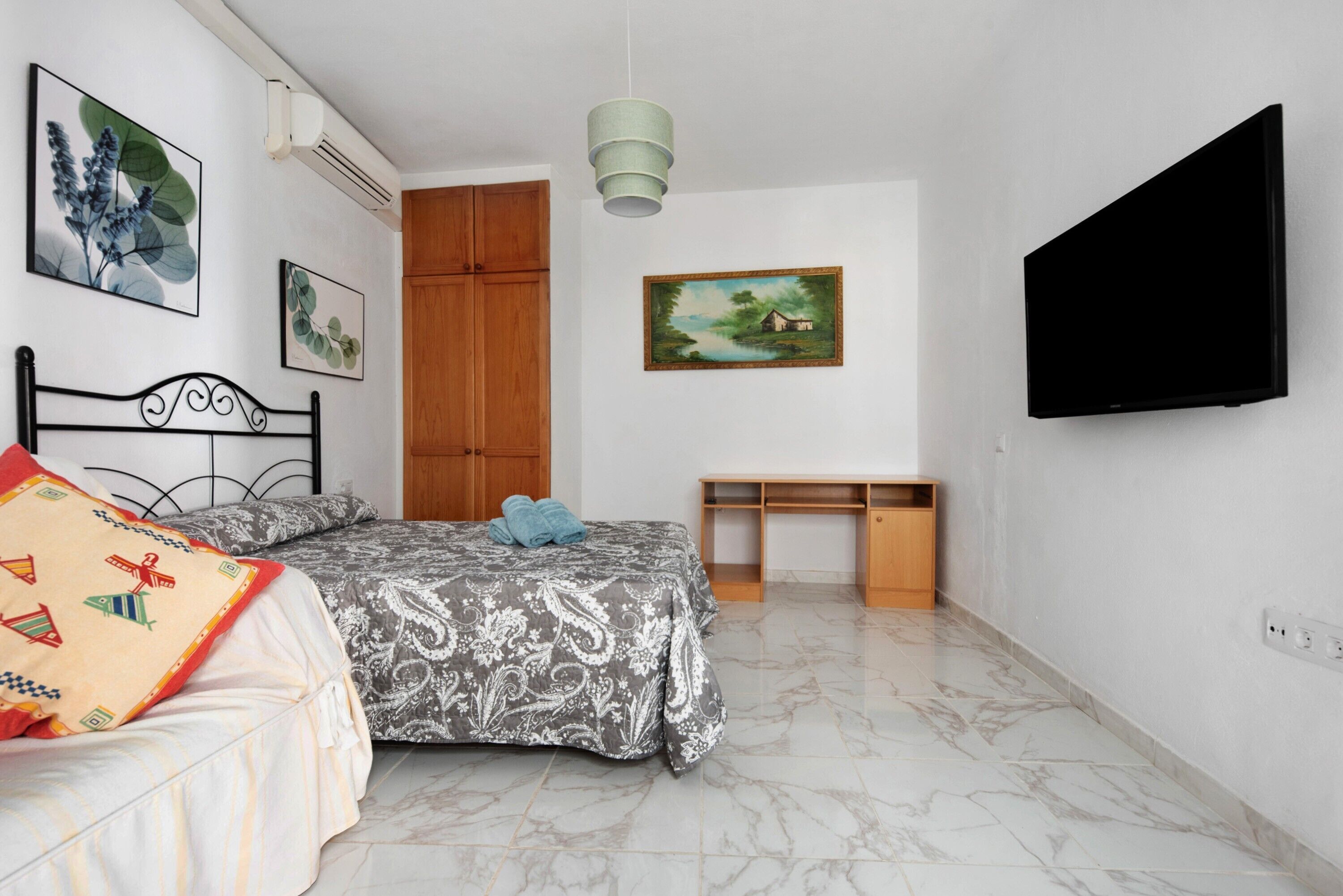 Una camera da letto con un letto, una scrivania, una TV e opere d'arte alle pareti.