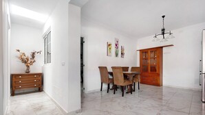 Un intérieur moderne comprenant un coin repas, un meuble en bois et un vase décoré de fleurs séchées.