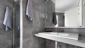 Une salle de bain moderne avec une douche à parois de verre, un lavabo blanc et un grand miroir.