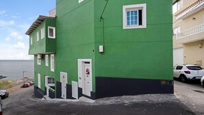 Un bâtiment écologique doté de nombreuses fenêtres, d’une porte et d’un petit balcon.