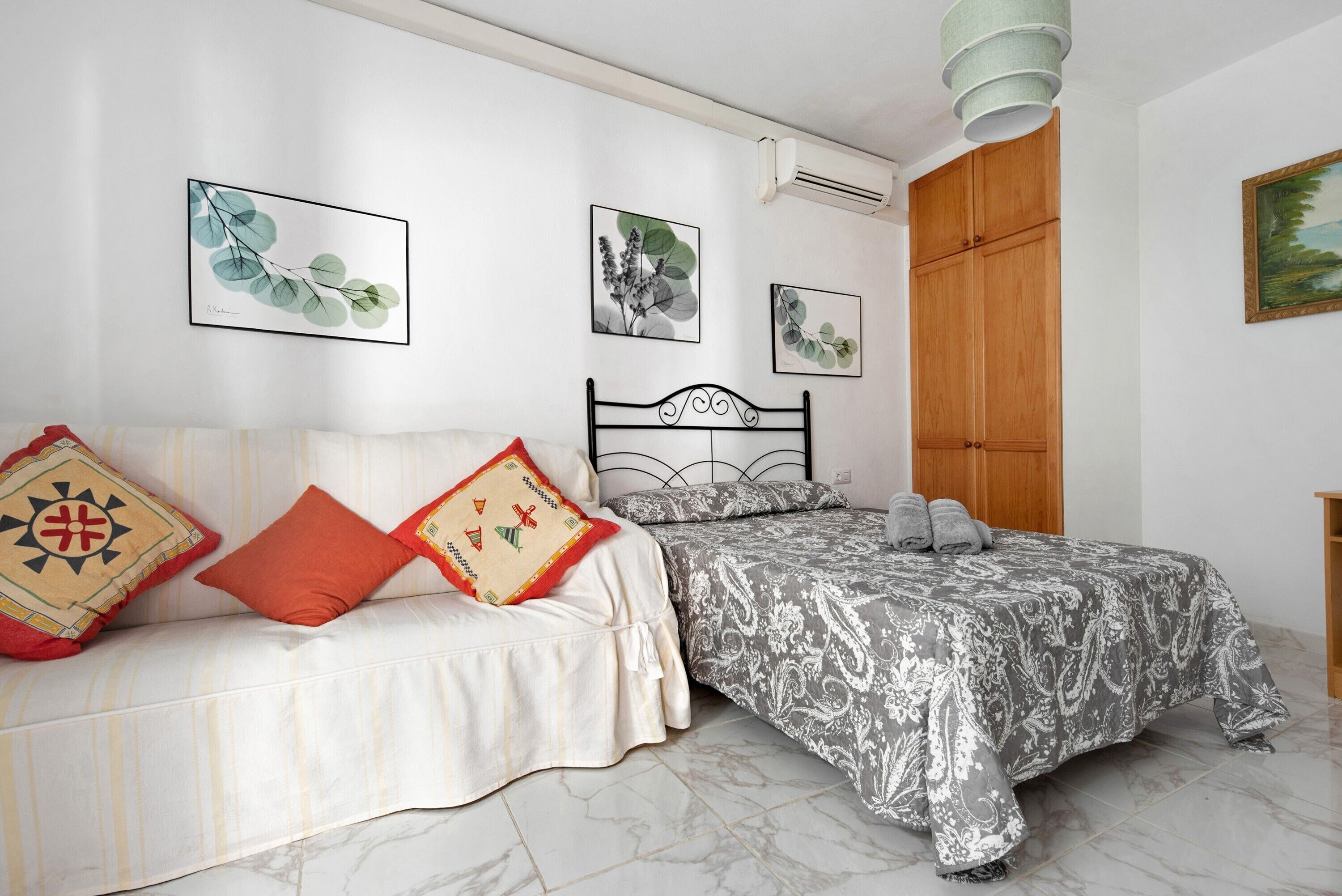 Ein Schlafzimmer mit Bett, Sofa, Kleiderschrank und Wandbildern.