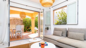 An open sliding glass door leading to an outdoor patio with a table and chairs, a sofa, and a hanging light fixture. - Holiday Home "Villa Sion" with Mountain Views, Pool, Wi-Fi & Terrace, Near Beaches (Cala Mendia)