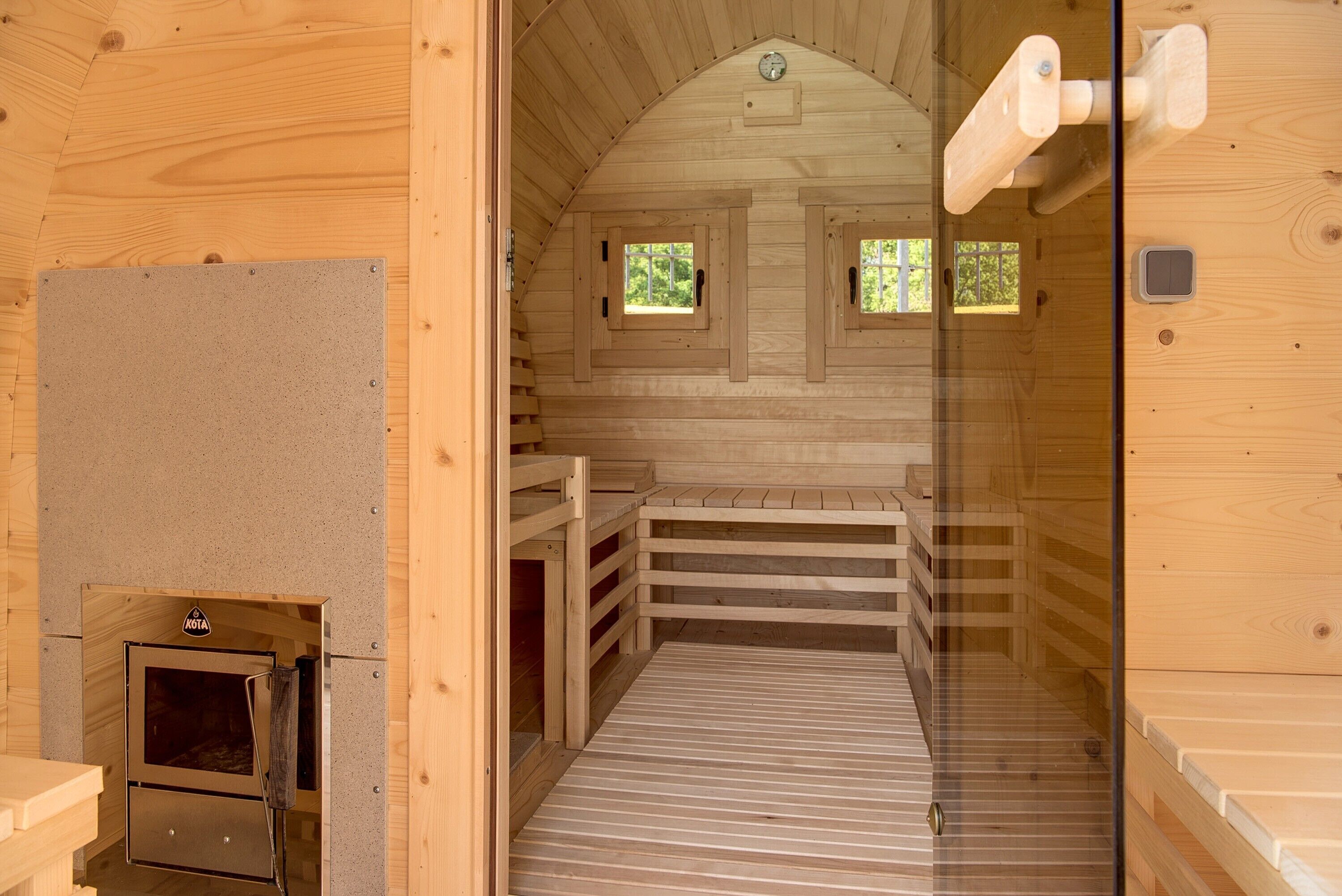 A wooden sauna with a bench, a small window, and a door.