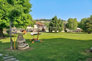 A grassy area with a swing set, a stone sculpture, and a signpost. - Beautiful "Iris Apartment," in Piedmont, with shared pool, garden and sauna (Cisterna d'Asti)