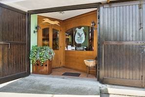 A wooden entrance with a glass door, a basket, and a chair outside. - Beautiful "Iris Apartment," in Piedmont, with shared pool, garden and sauna (Cisterna d'Asti)