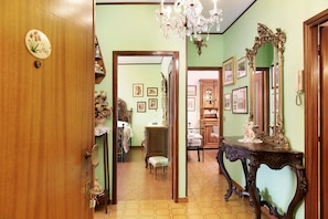 A hallway with a wooden door, a mirror, and a table with a decorative item. - Beautiful "Iris Apartment," in Piedmont, with shared pool, garden and sauna (Cisterna d'Asti)