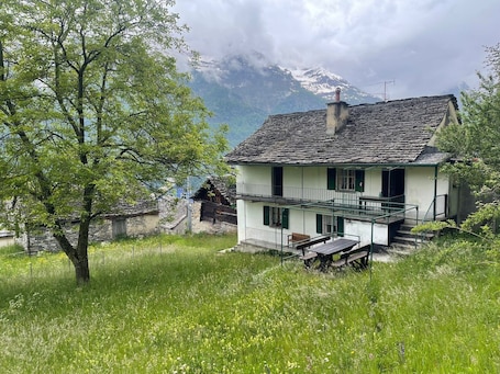 A two-story house with a balcony, surrounded by lush greenery and a mountainous backdrop.. Apartment "La Casa di Sissy" with Garden & Mountain View, Wi-Fi, Garden & Terrace; Pet Friendly
