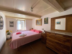 A bedroom with a bed, dresser, vanity, and artwork on the walls.