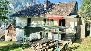 Un bâtiment à deux étages doté d’un balcon, d’une table en bois et d’une chaise.