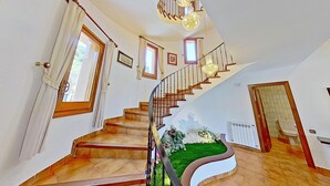 A staircase with wooden steps and a black railing, leading to a landing with a chandelier. - PREMIUM HABITAT CAN FERRER (Arenys de Munt)