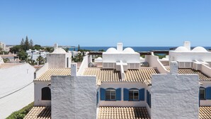 A coastal residential area with white buildings and blue shutters, featuring a clear view of the sea. - Villa 'Mourisca' with Shared Pool, Private Garden and Wi-Fi (Alporchinhos)