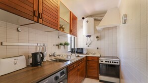 A kitchen with wooden cabinets, a microwave, a toaster, a washing machine, and a stove. - Villa 'Mourisca' with Shared Pool, Private Garden and Wi-Fi (Alporchinhos)