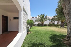 A courtyard with a palm tree, a door, and a white building with a balcony. - Villa 'Mourisca' with Shared Pool, Private Garden and Wi-Fi (Alporchinhos)