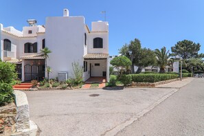 A white building with a tiled roof, a small entrance, and a paved driveway. - Villa 'Mourisca' with Shared Pool, Private Garden and Wi-Fi (Alporchinhos)
