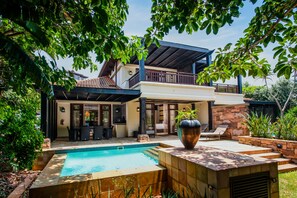 A two-story house with a swimming pool, outdoor seating, and a large planter. - The Capital Zimbali (Ballito)