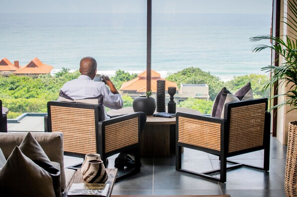 A man sitting at a table with a view of the ocean. - The Capital Zimbali (Ballito)