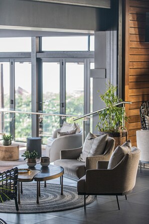 A modern living room with a sofa, armchairs, a coffee table, and a potted plant. - The Capital Zimbali (Ballito)