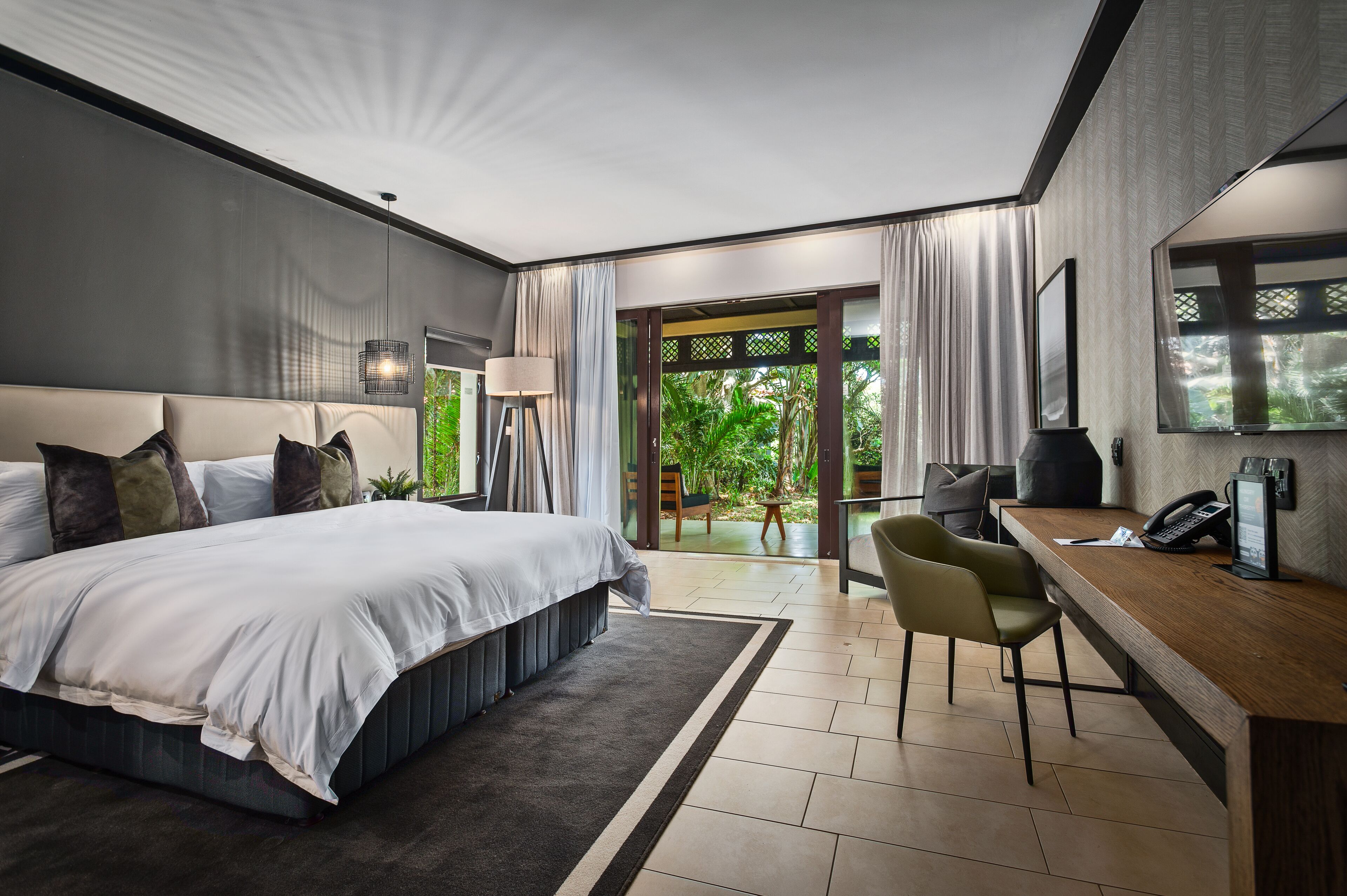 Habitación de hotel moderna con una cama grande, un escritorio y vistas a zonas verdes.