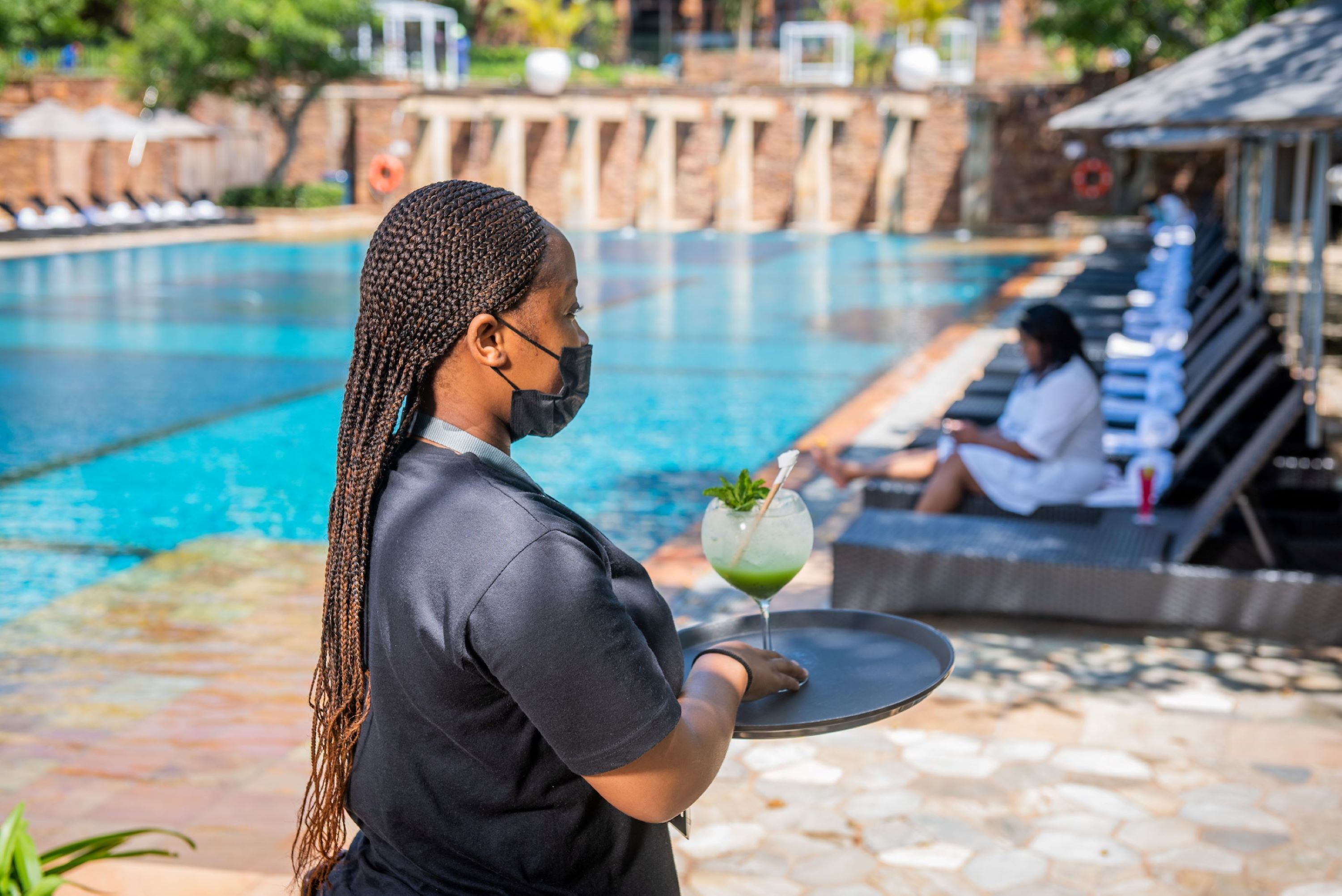 A person serving a drink by a poolside.