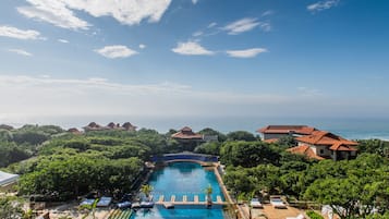 Um resort com piscina rodeada por vegetação exuberante e vista para o mar.