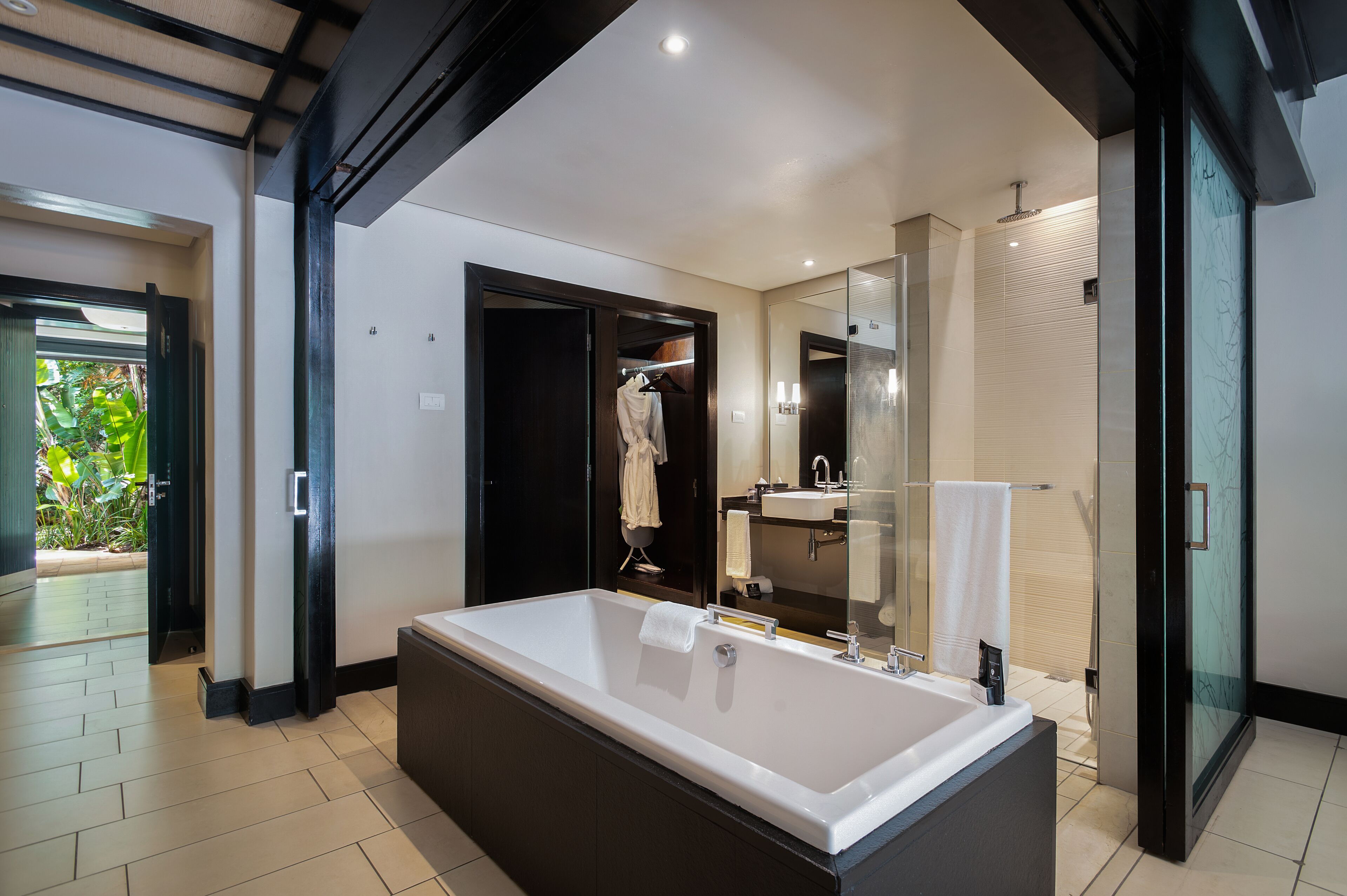 Un baño moderno con una bañera grande, cabina de ducha de vidrio y vestidor.
