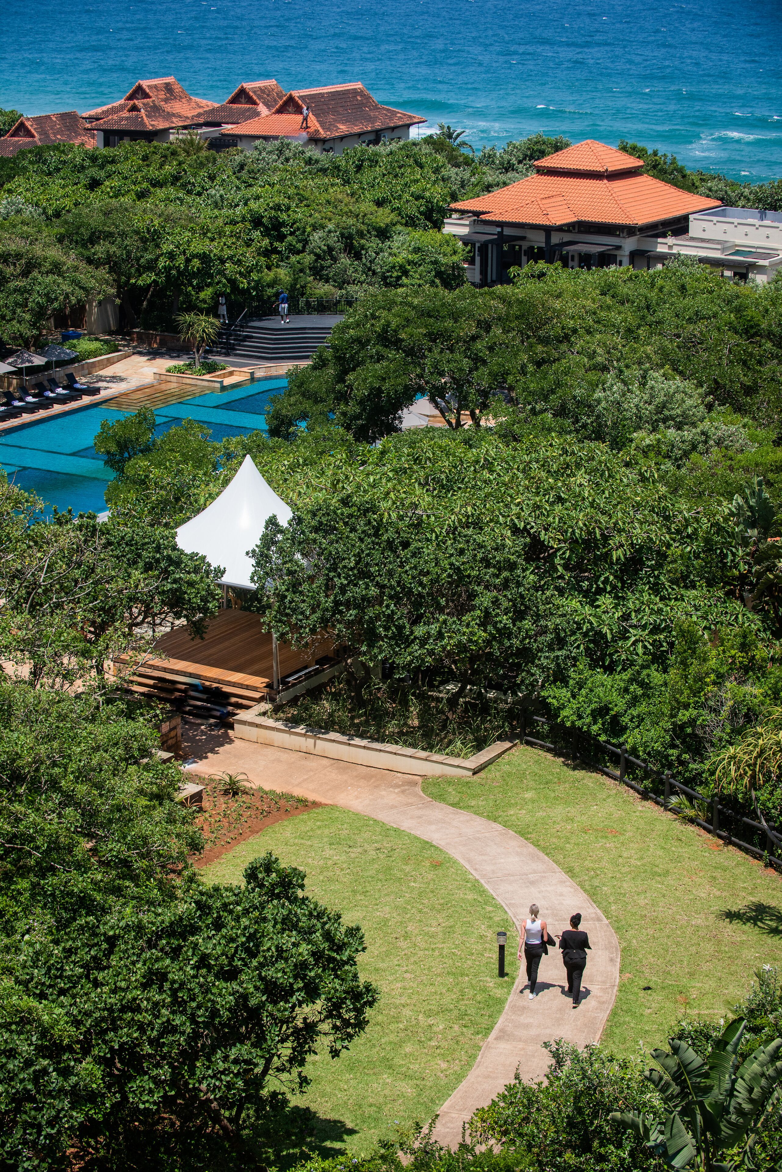 A resort with a swimming pool, a covered pavilion, and a view of the ocean.