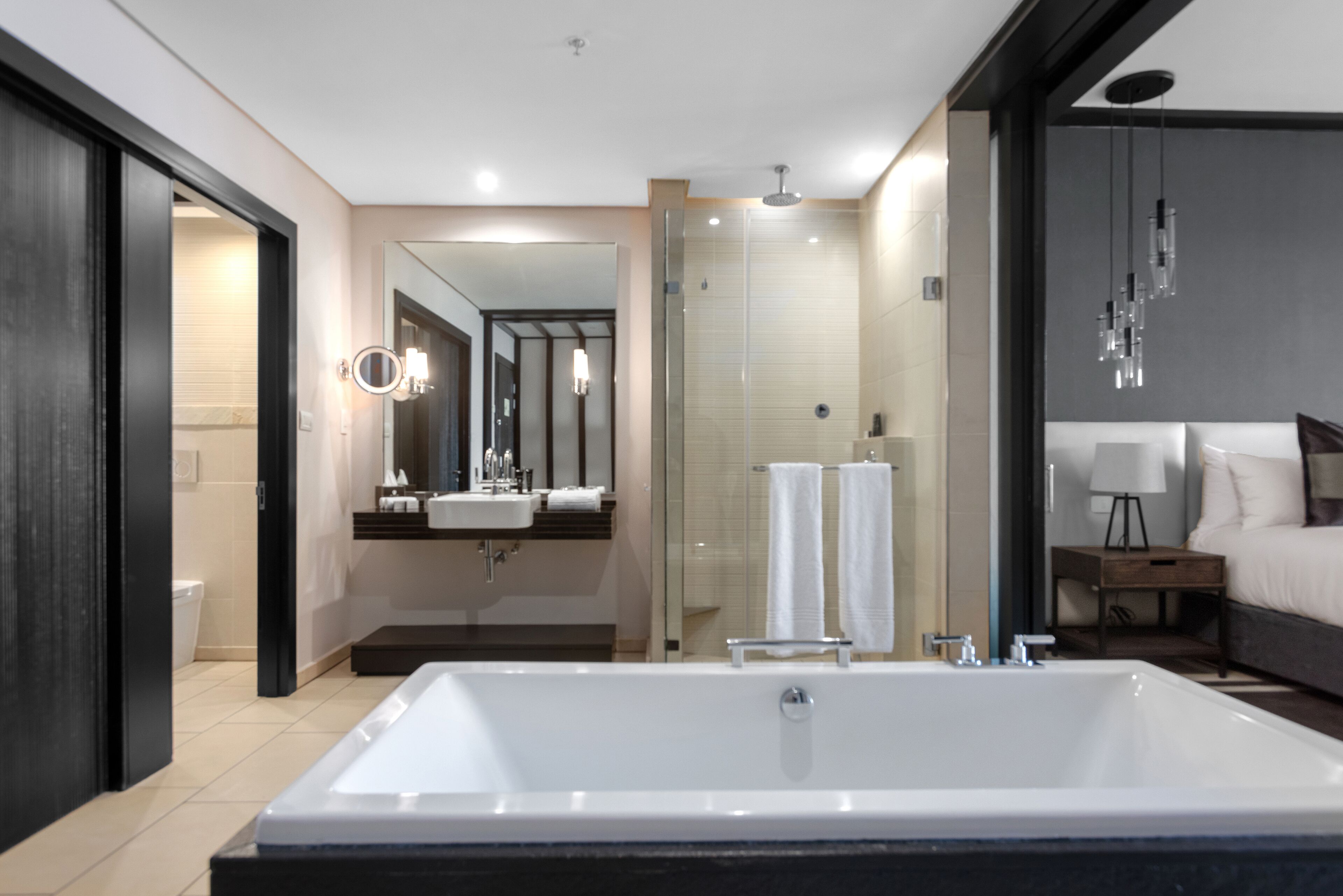 Une salle de bain moderne dotée d’une grande baignoire, d’une douche séparée et d’un meuble-lavabo avec un miroir.
