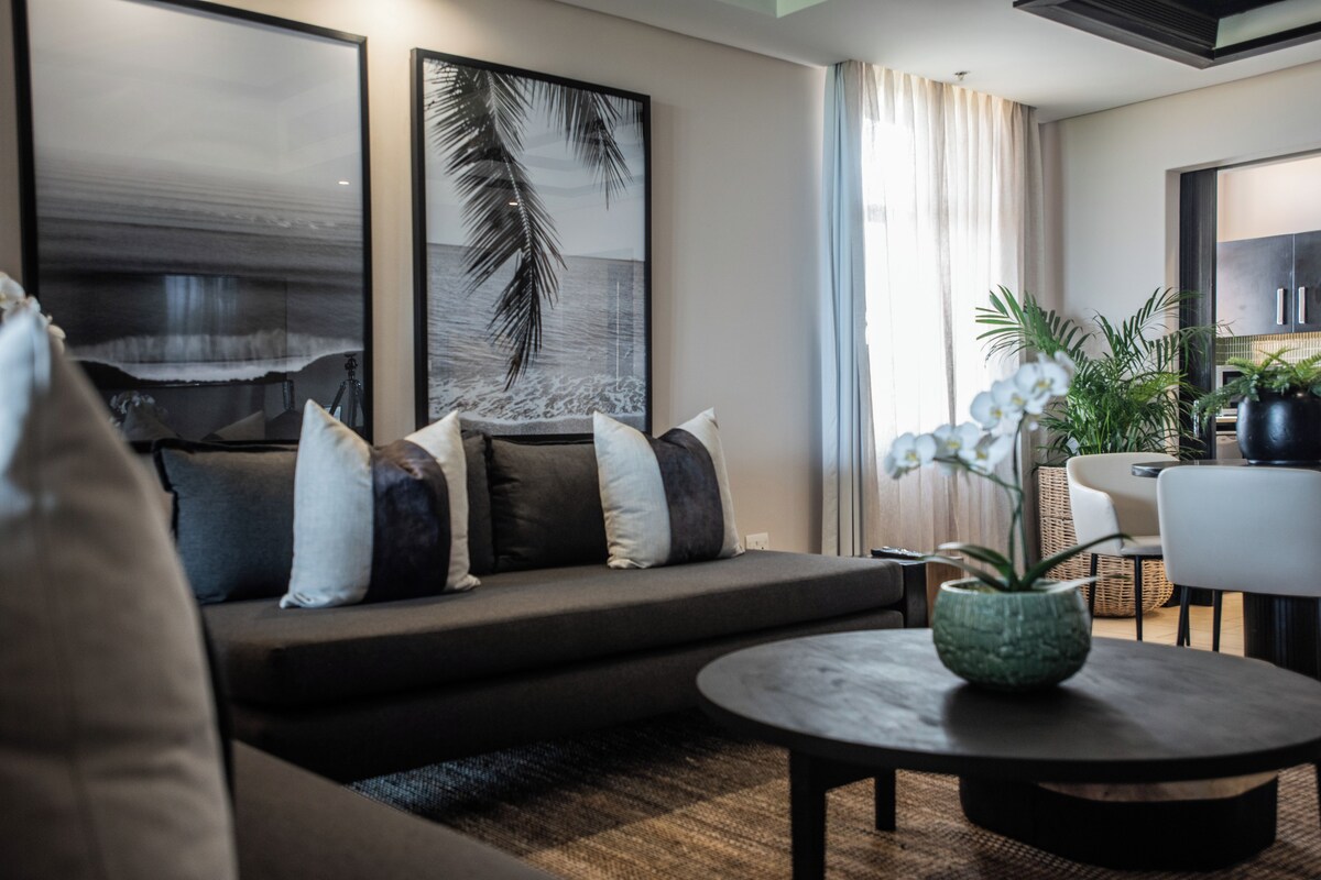 A modern living room with a sofa, a coffee table, and a dining area with chairs.
