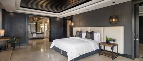 A modern bedroom with a large bed, bedside table, and a view into the bathroom.