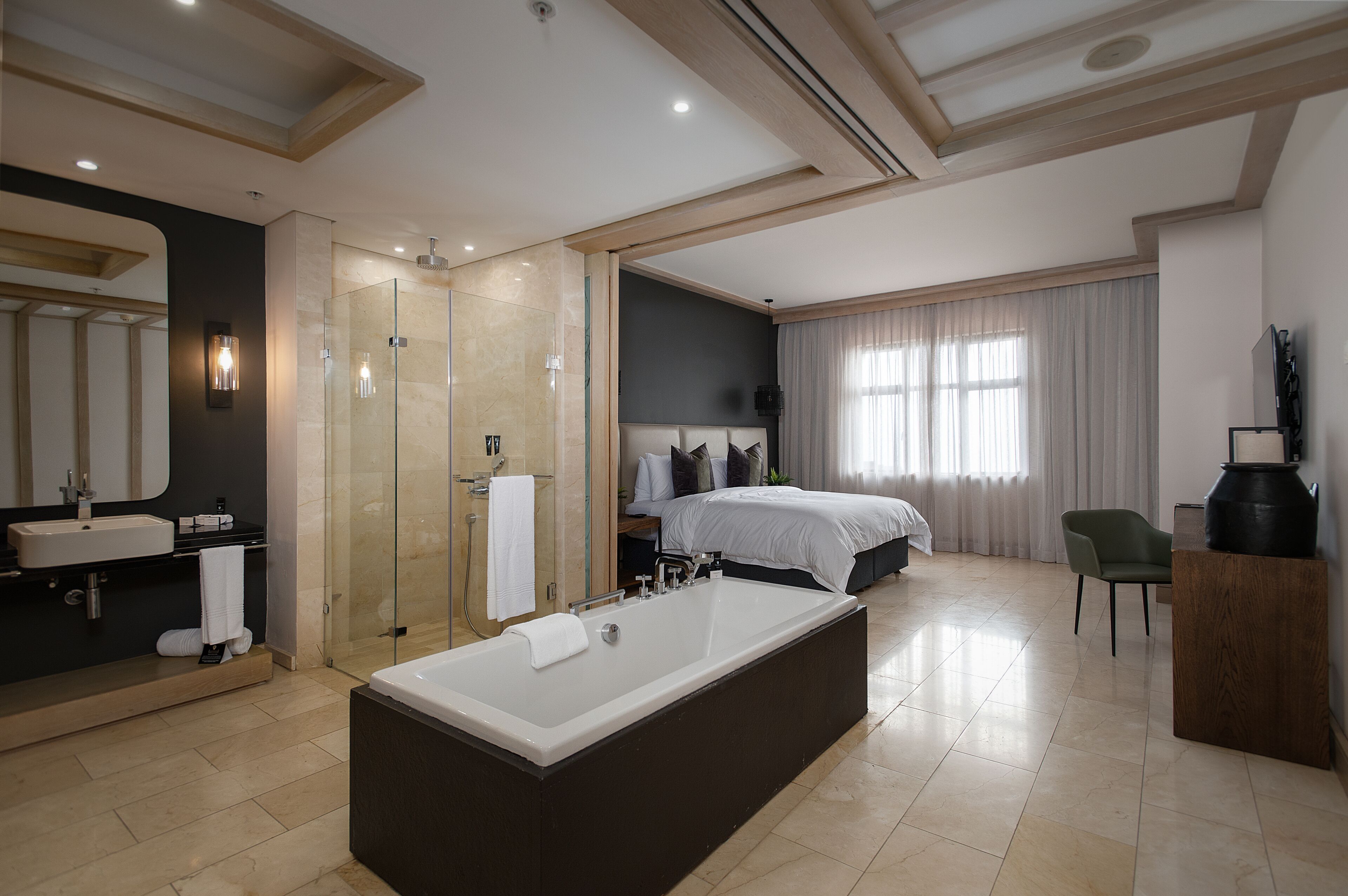A modern bathroom with a large bathtub, a glass-enclosed shower, and a vanity with a sink and mirror.