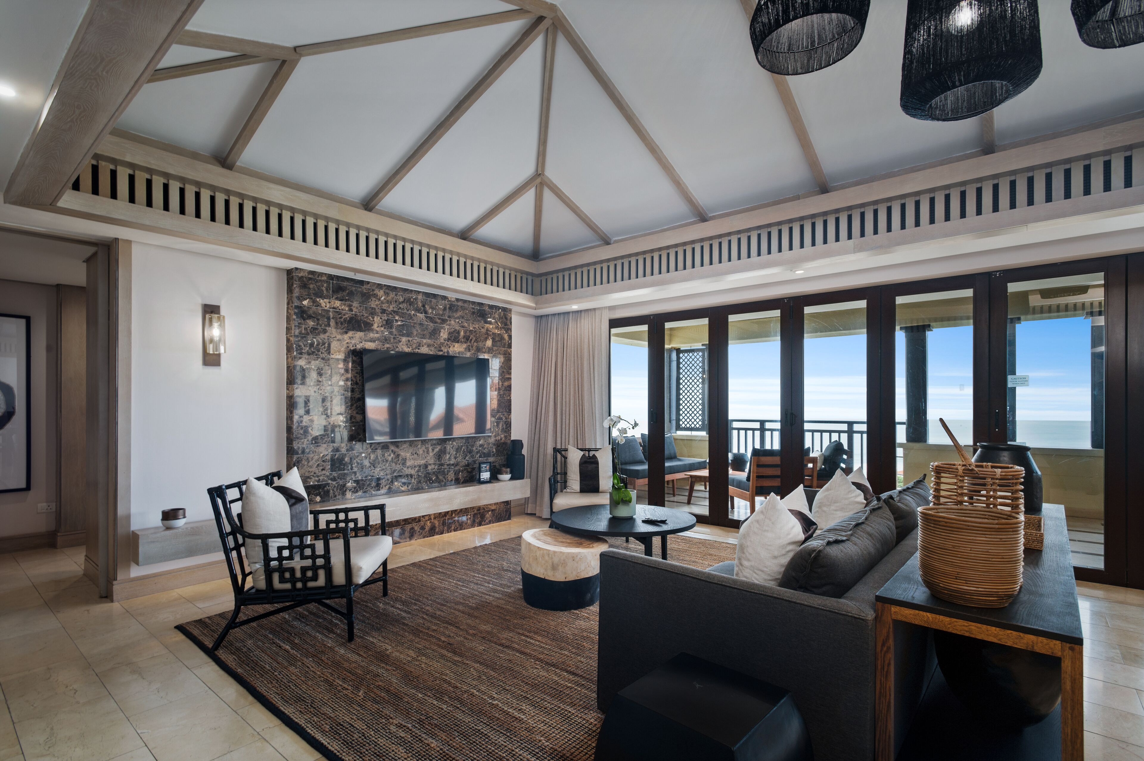 A spacious living area with a stone fireplace, comfortable seating, and large windows overlooking the ocean.