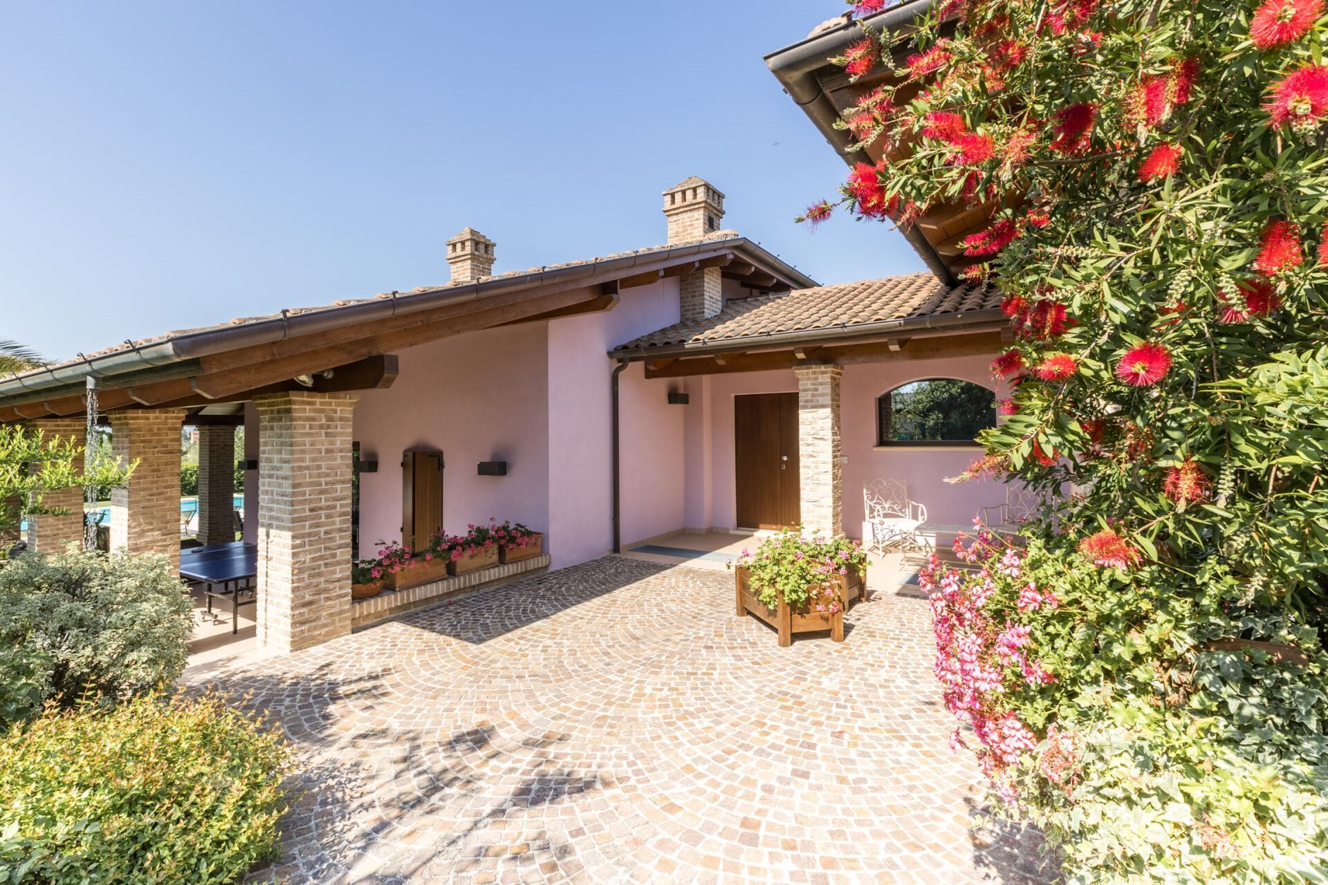 A house with a tiled patio, brick walls, and a wooden pergola.