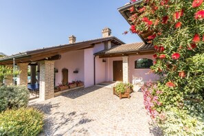 Une maison avec une terrasse carrelée, des murs en briques et une pergola en bois.