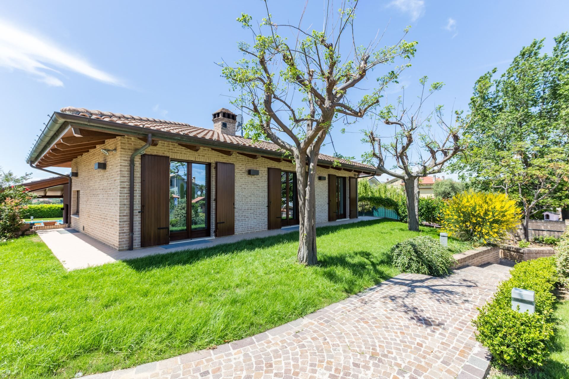 A modern house with a brick exterior, large windows, and a well-maintained lawn.