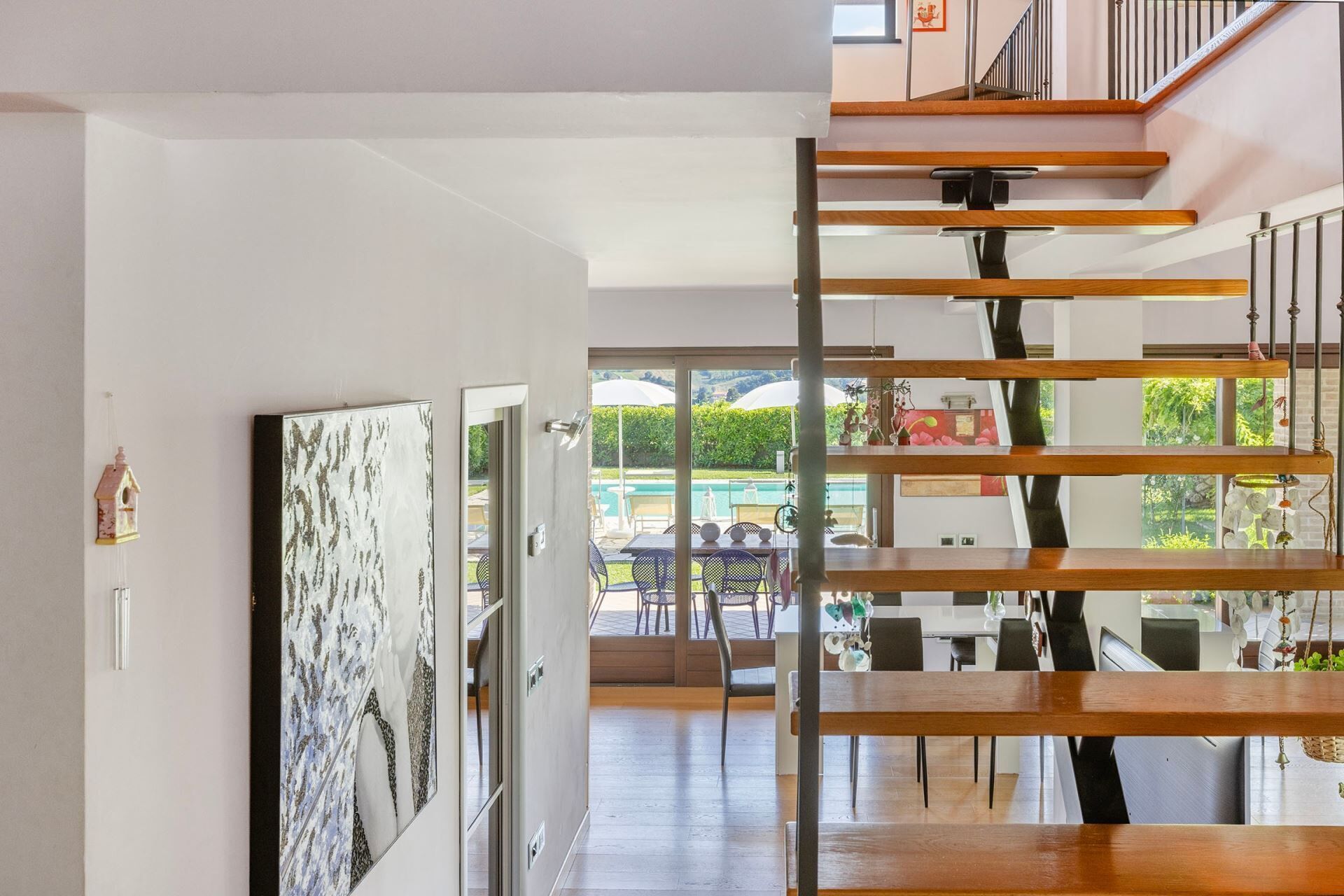 Un interno moderno con una scala, una zona pranzo e vista su una piscina all'aperto.