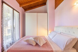 Ein Schlafzimmer mit einem Bett, zwei Kissen, einem Kleiderschrank und einem Fenster mit Vorhängen.
