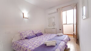 A bedroom with a large bed, a dresser, an air conditioning unit, and a window with curtains. - 2 bedroom apartment 200 m. from the beach (Alcúdia)