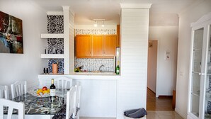 A modern kitchen with white cabinetry, a central island, and a dining area with a glass table and white chairs. - 2 bedroom apartment 200 m. from the beach (Alcúdia)