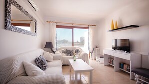A modern living room with a sofa, a coffee table, a TV, and a bookshelf. - 2 bedroom apartment 200 m. from the beach (Alcúdia)