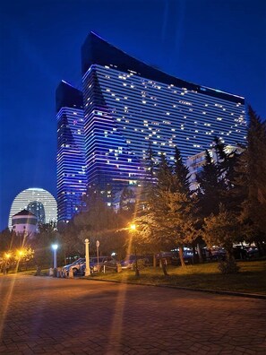 Un hotel moderno con una fachada de vidrio destacada, varios pisos y una estructura de cúpula al fondo.