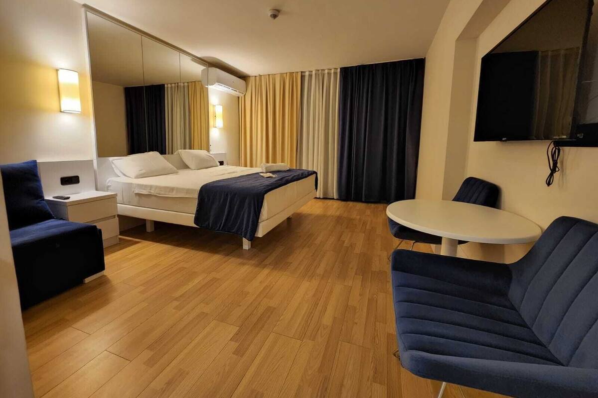 Une chambre d’hôtel équipée d’un lit, d’une table de chevet, d’une lampe, d’une chaise et d’un téléviseur fixé au mur.