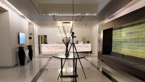 A modern lobby with a reception desk, a camera on a tripod, and a large digital screen on the wall. - Orbi City Apartment (Batumi)